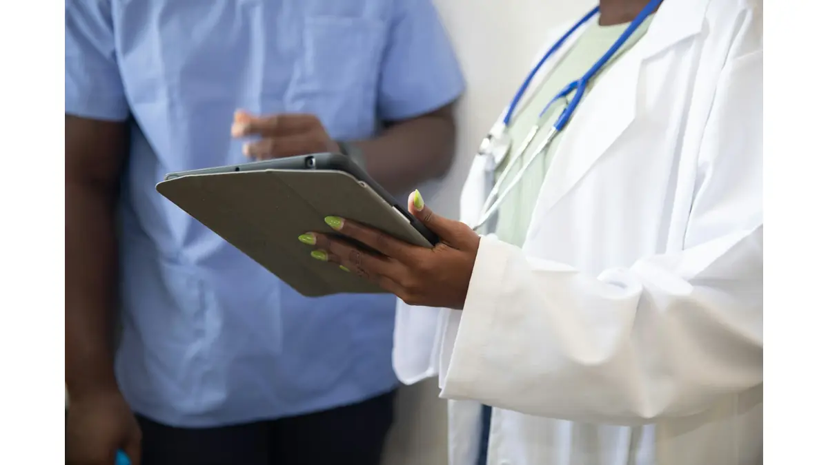 Beyaz önlüklü doktor, muayenede hastaya tabletten bilgileri gösteriyor