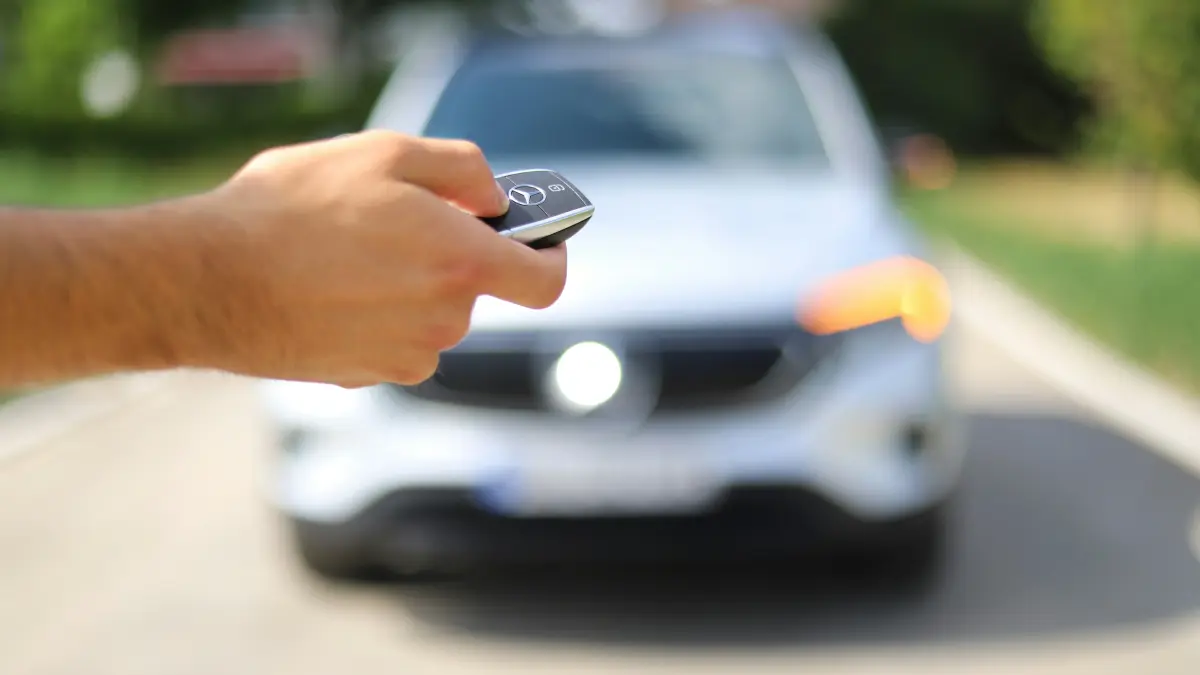 Autoschlüssel in der Hand vor einem Neuwagen