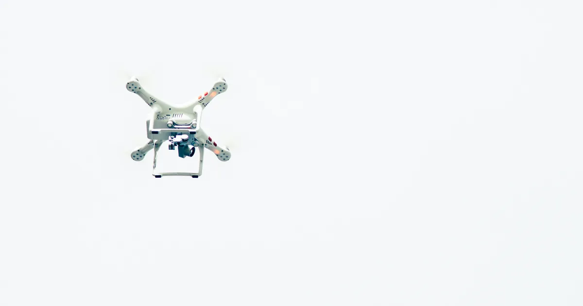 Drohne mit Kamera im Flug vor hellem Himmel